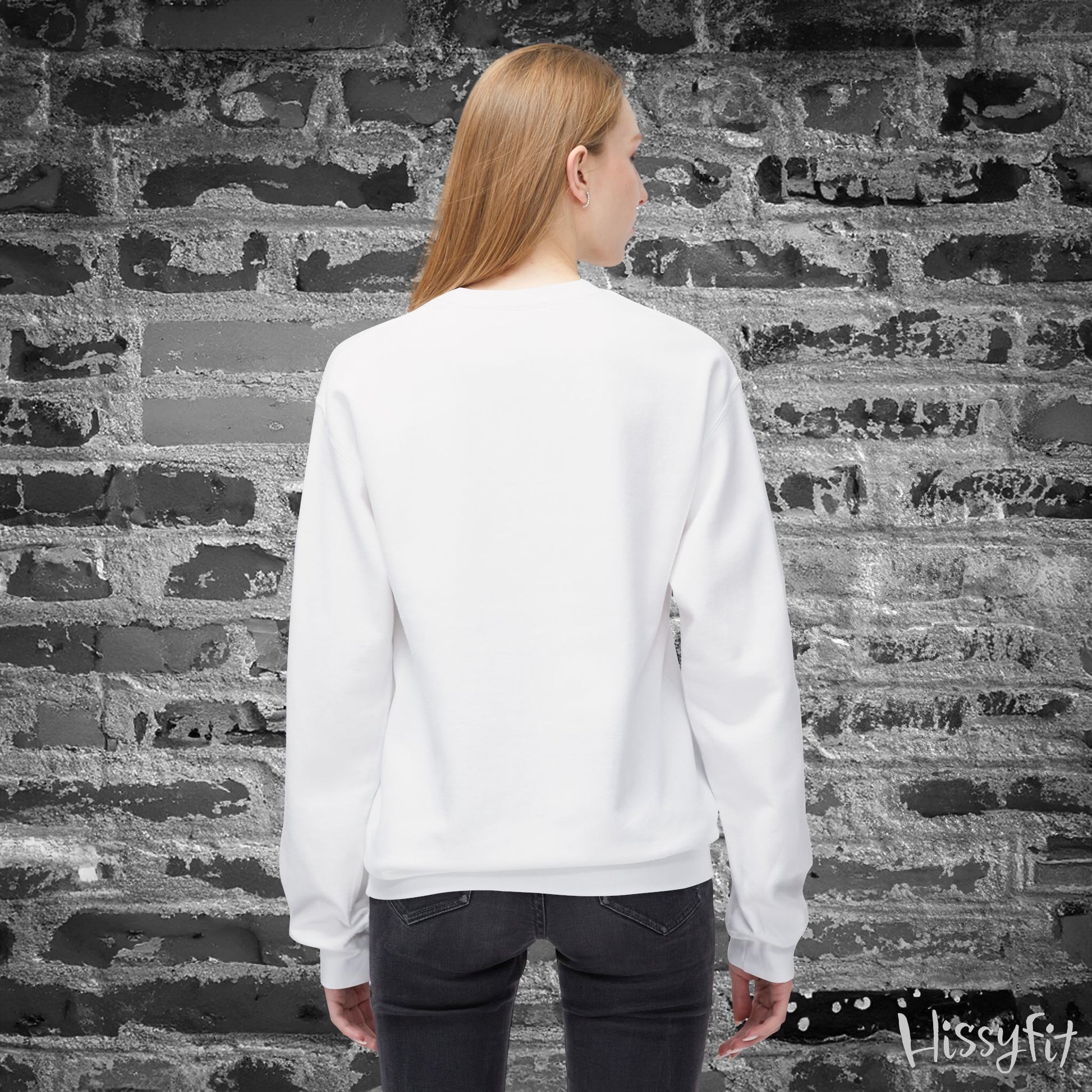 Person wearing a white sweatshirt standing against a textured brick wall.