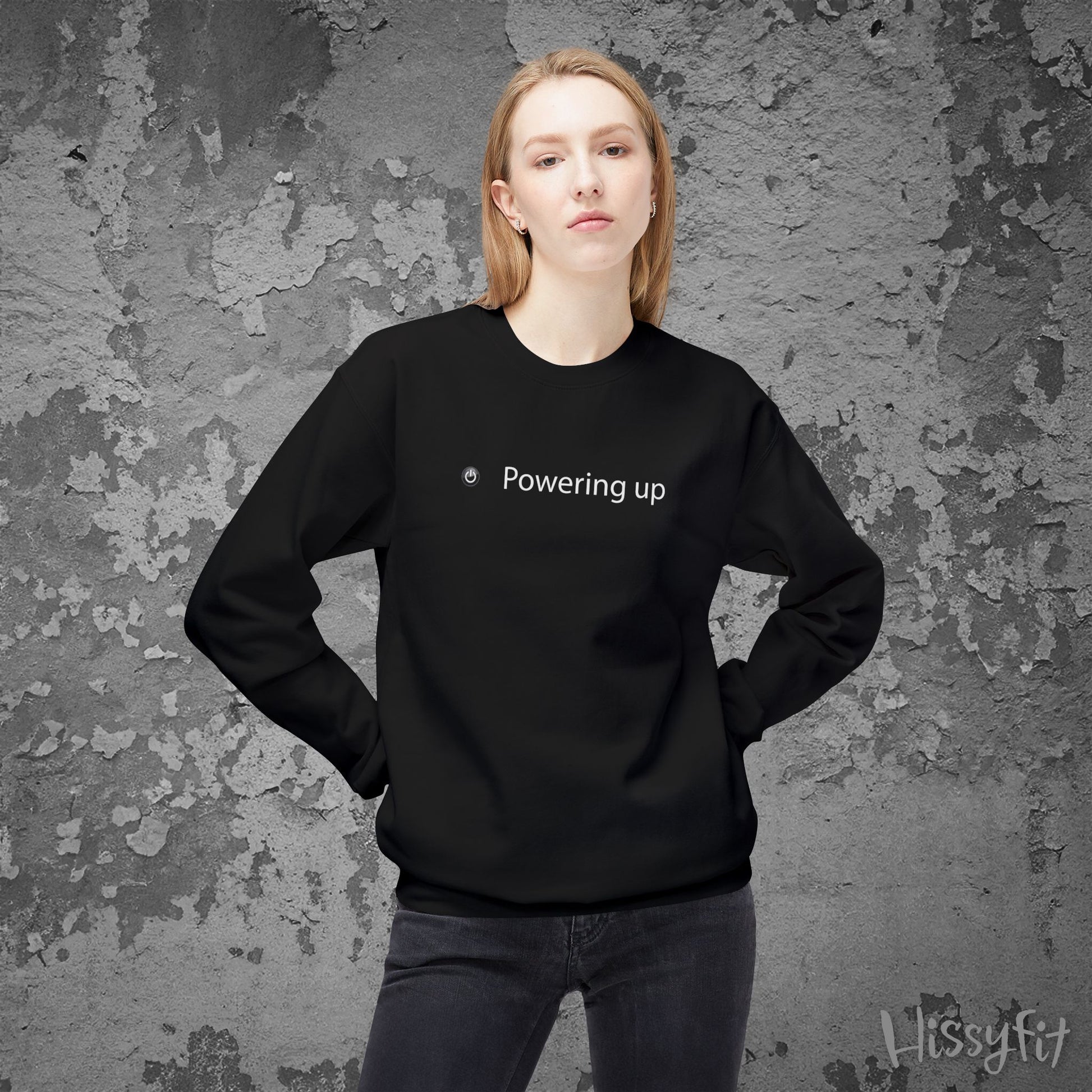 Person wearing a black sweatshirt with 'Powering up' text against a textured gray background