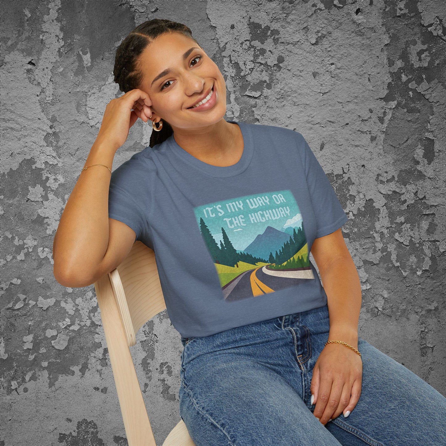 Person wearing a blue t-shirt with a graphic design of a road and mountains and text 'It's my way or the highway' on a textured gray background