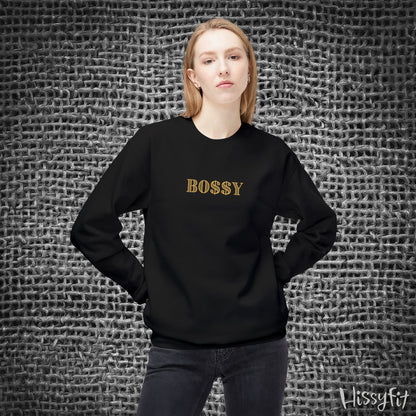 Person wearing a black sweatshirt with 'BOSSY' text against a textured gray background