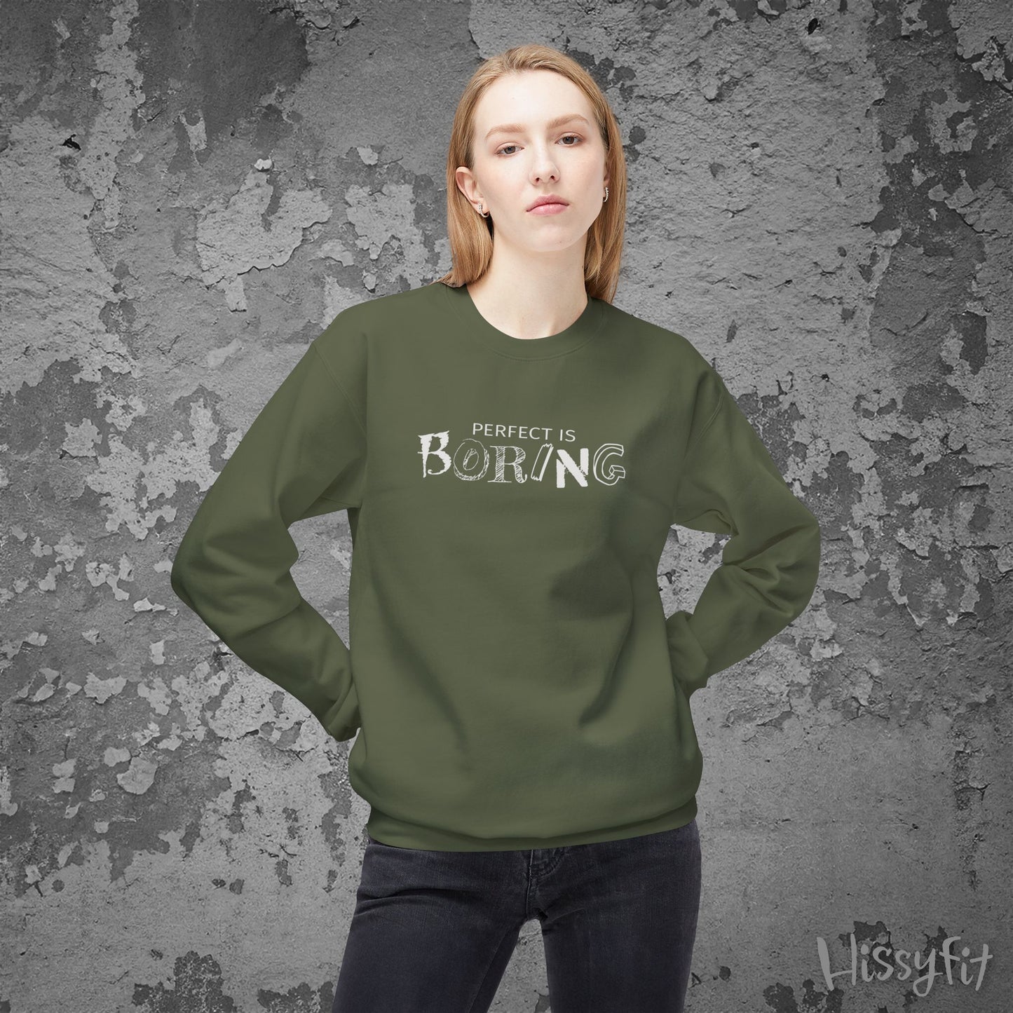 Person wearing a green sweatshirt with 'PERFECT IS BORING' text against a textured gray background