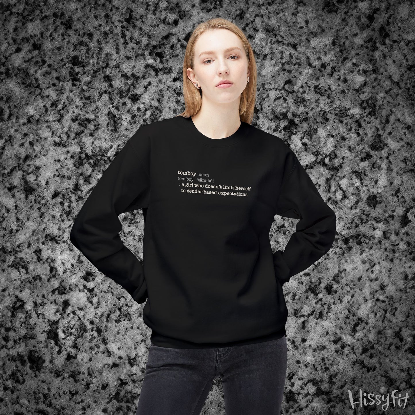 Person wearing a black sweatshirt with text definition of "Tomboy" on a gray and black speckled background