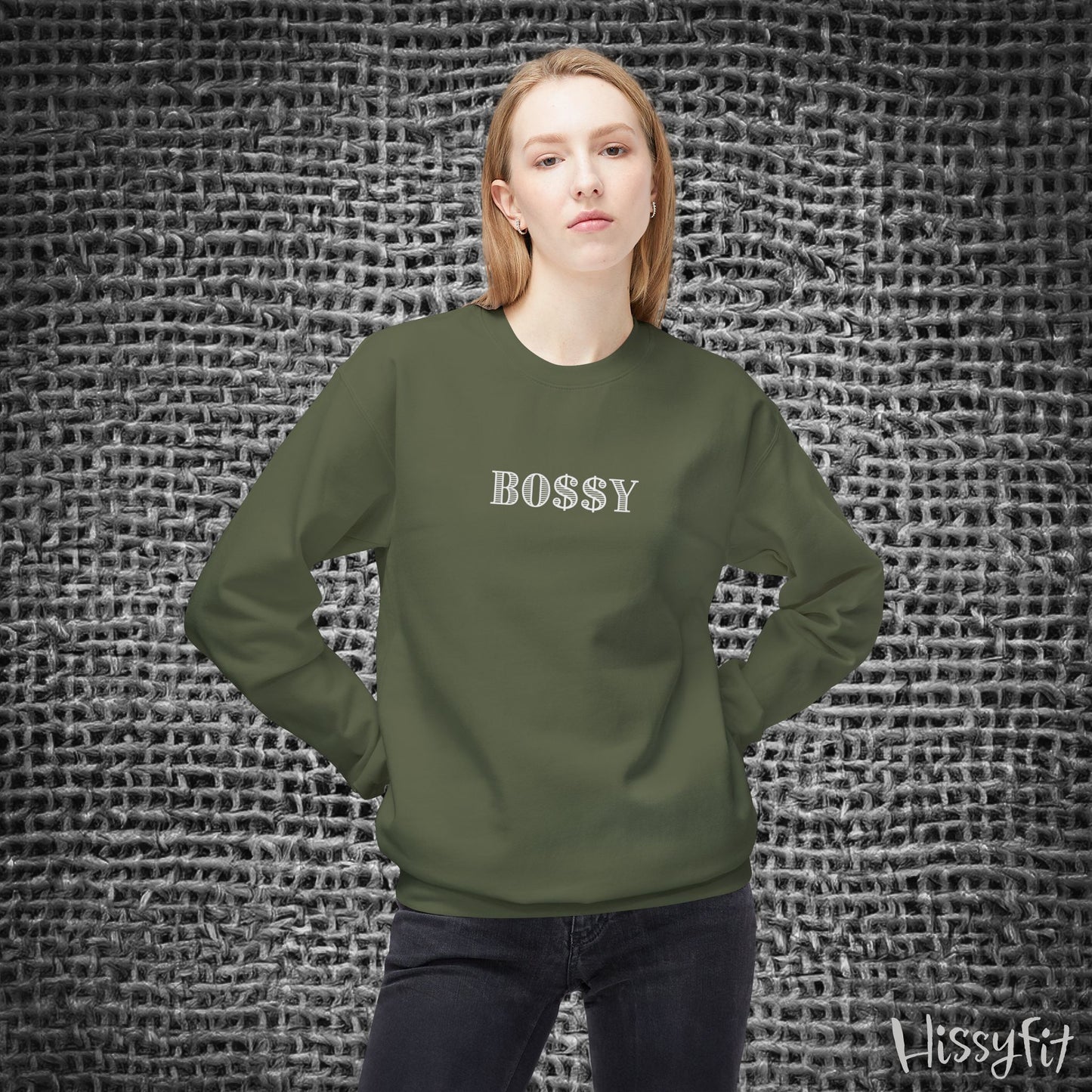 Person wearing a green sweatshirt with 'BOSSY' text against a textured gray background