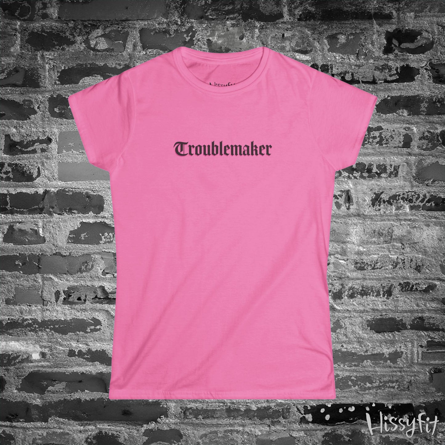 Pink t-shirt with 'Troublemaker' text on a brick wall background
