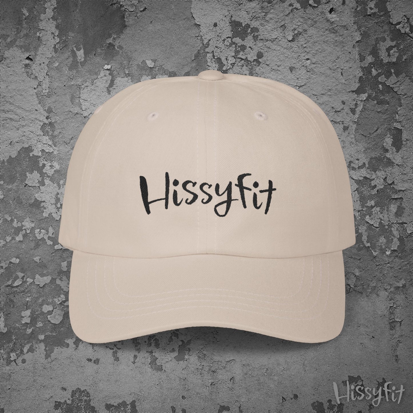 Beige cap with 'Hissyfit' text on a textured gray background