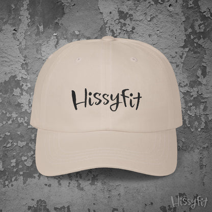 Beige cap with 'Hissyfit' text on a textured gray background