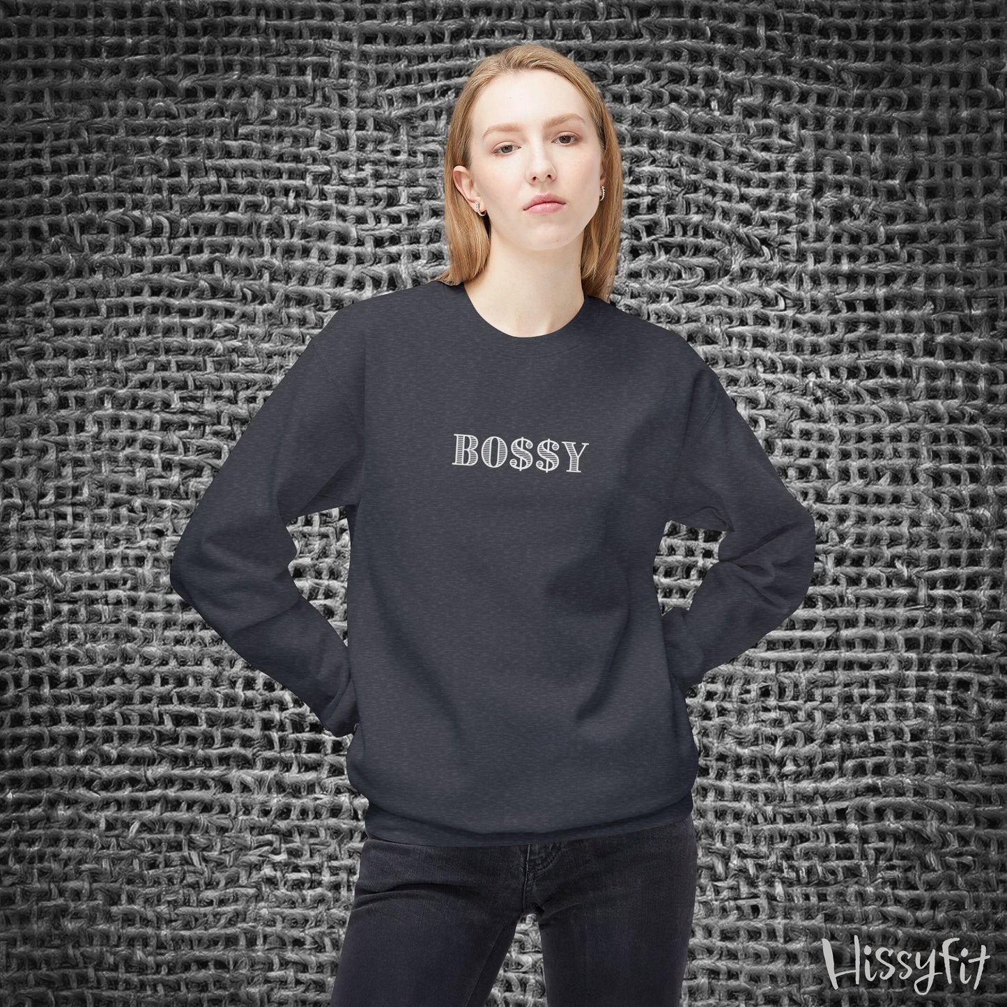 Person wearing a black sweatshirt with 'BOSSY' text against a textured gray background