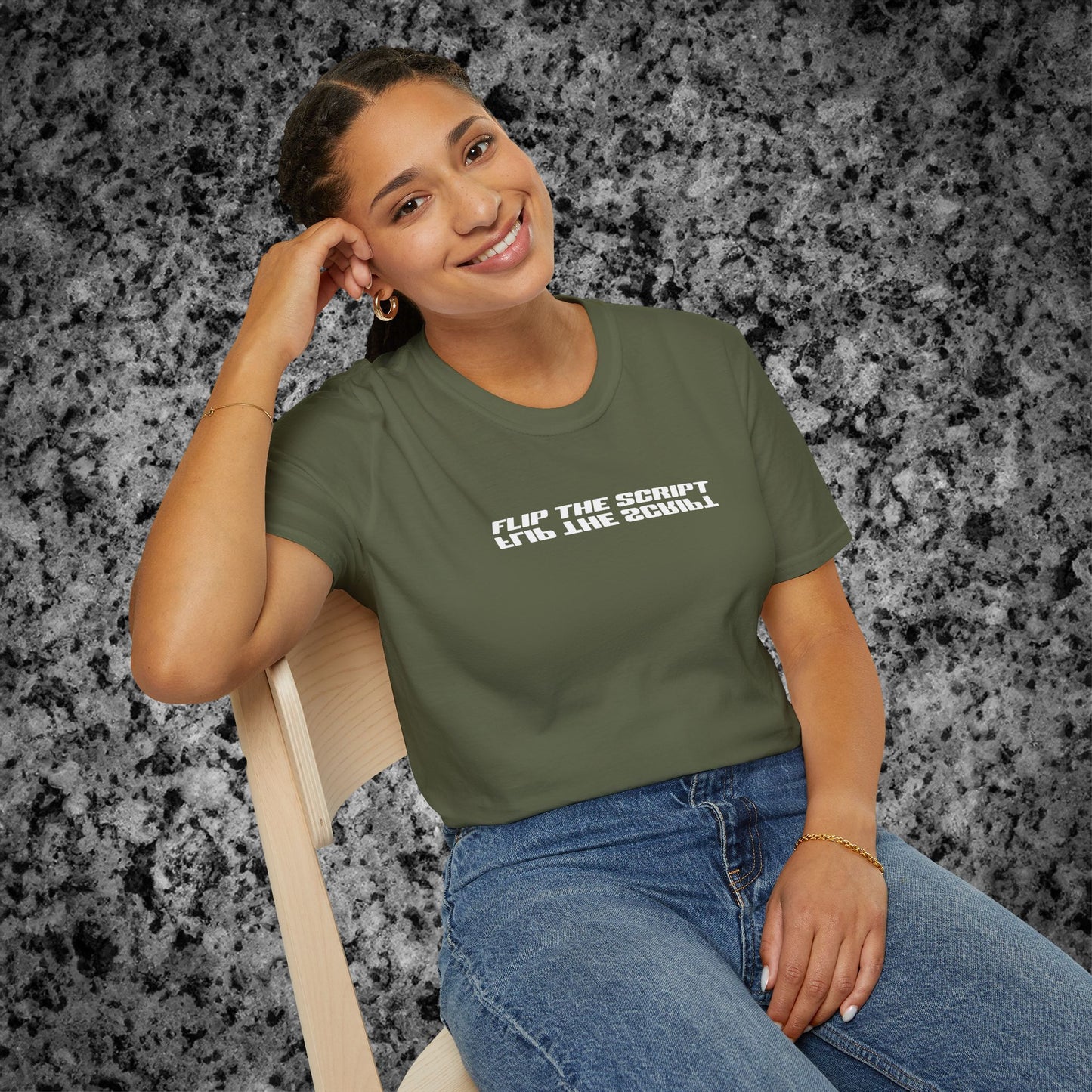 Person wearing a green t-shirt with text 'Flip the script', sitting on a chair against a textured gray background