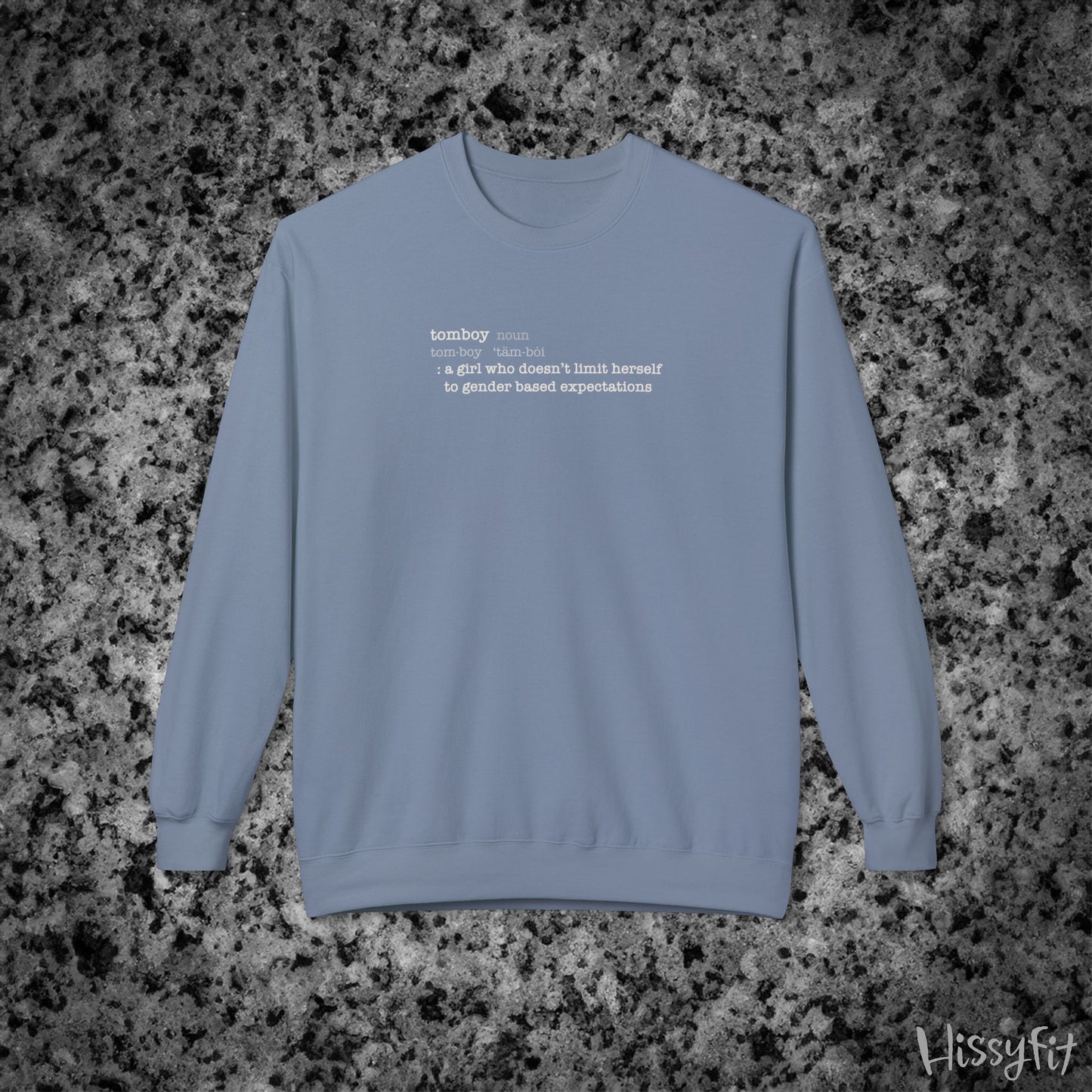 Blue sweatshirt with text definition of "Tomboy" on a gray and black speckled background