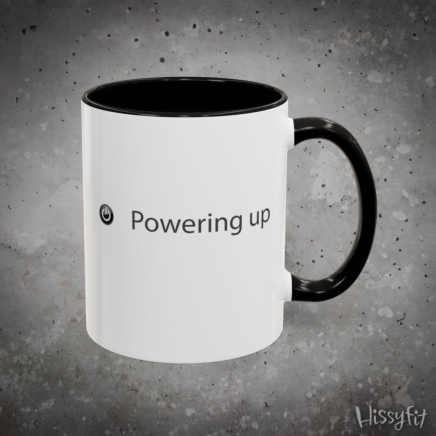 White mug with black interior and handle on a gray background, featuring the text 'Powering up' and a logo.
