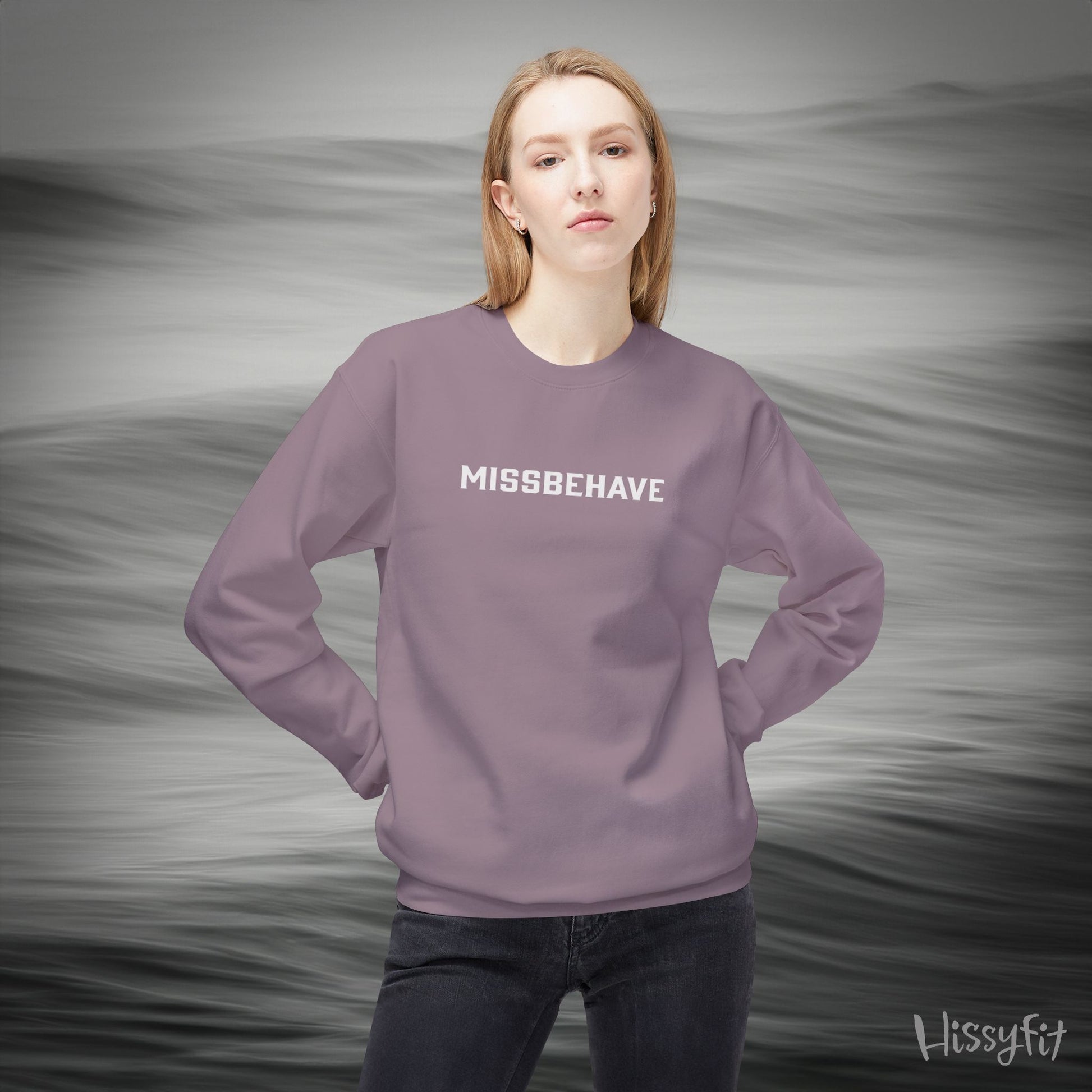 Person wearing a purple sweatshirt with 'MISSBEHAVE' text against a gray background