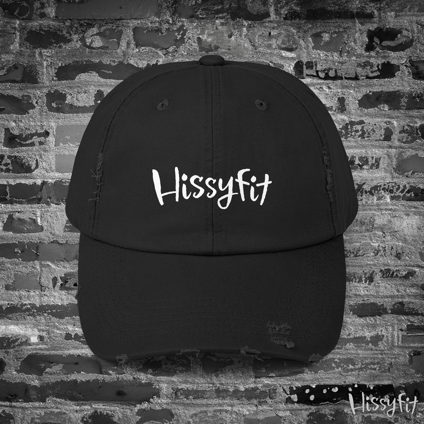 Black cap with 'Hissyfit' logo on a brick wall background