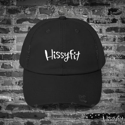 Black cap with 'Hissyfit' logo on a brick wall background