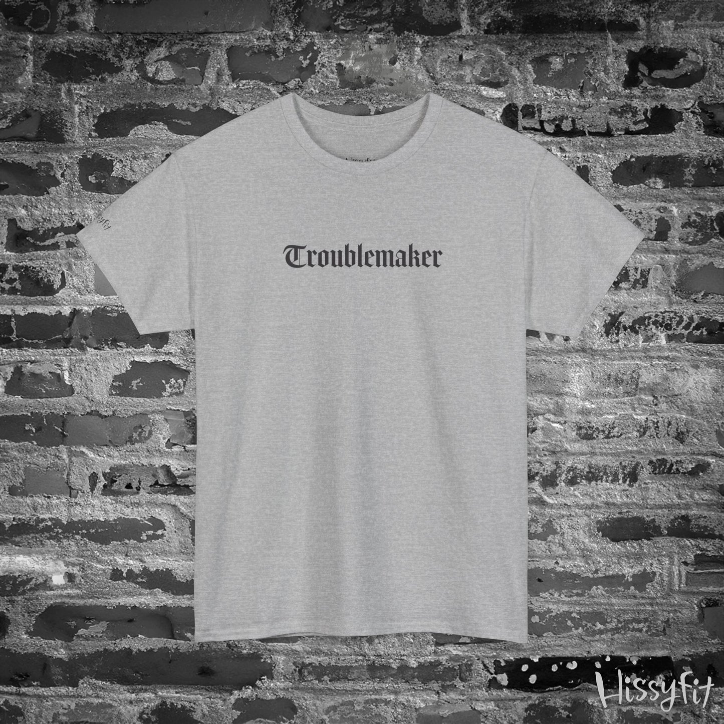 Gray t-shirt with 'Troublemaker' text on a brick wall background