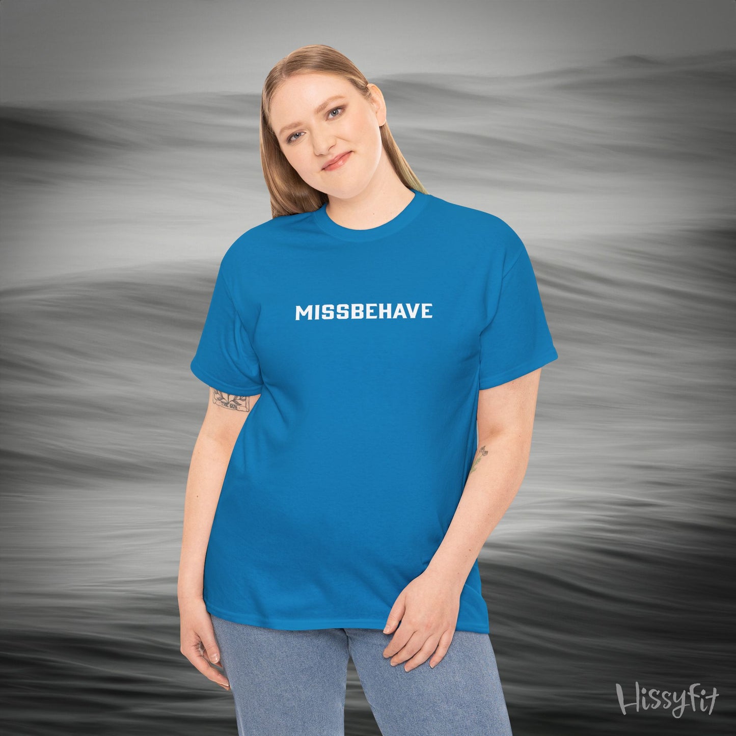 Person wearing a blue 'MISSBEHAVE' t-shirt with a gray background