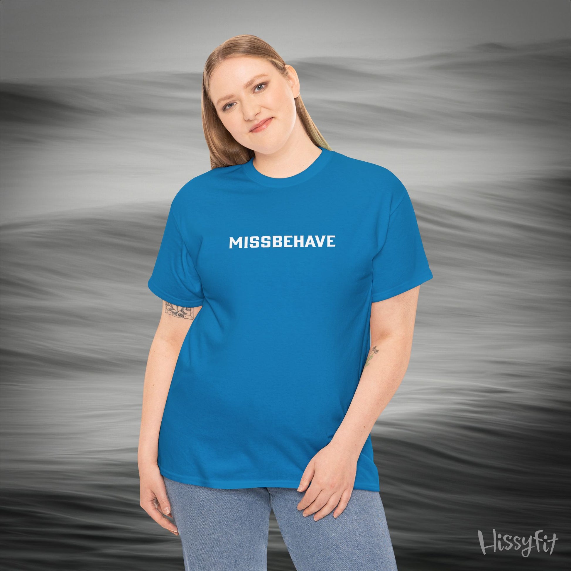 Person wearing a blue 'MISSBEHAVE' t-shirt with a gray background