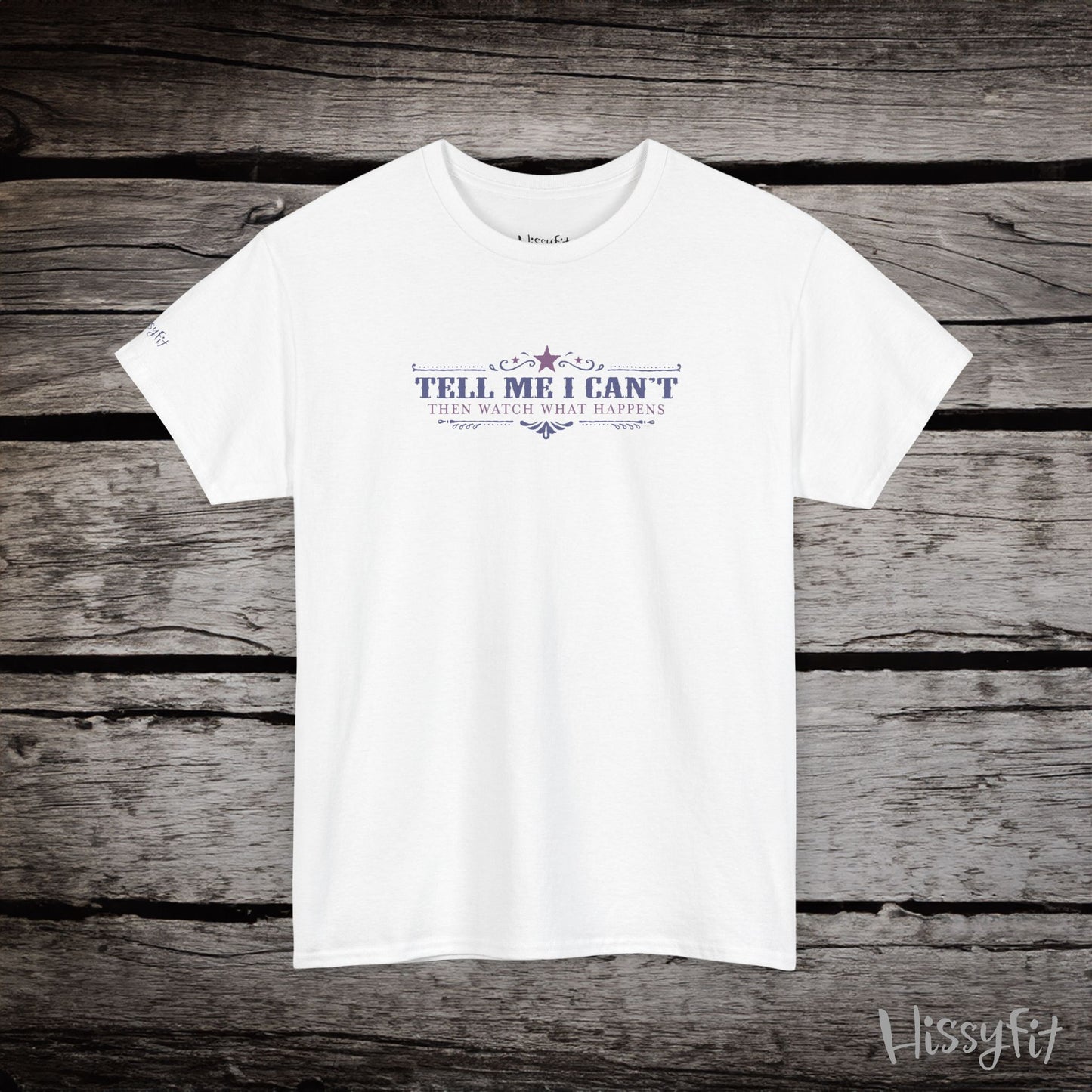 White t-shirt with text 'Tell me I can't then watch what happens' on a wooden surface, featuring the brand 'Hissyfit'.