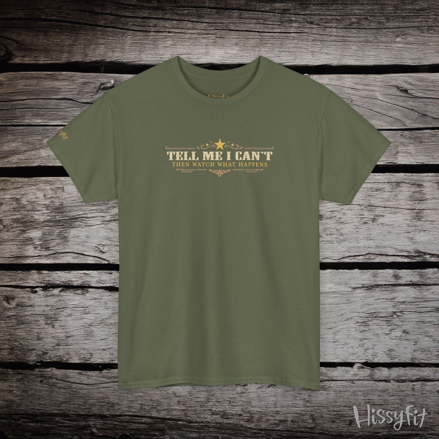 Green t-shirt with text 'Tell me I can't then watch what happens' on a wooden surface, featuring the brand 'Hissyfit'.