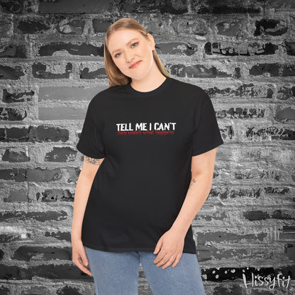 Person wearing a black t-shirt with text 'Tell me I can't then watch what happens' in front of a textured wall