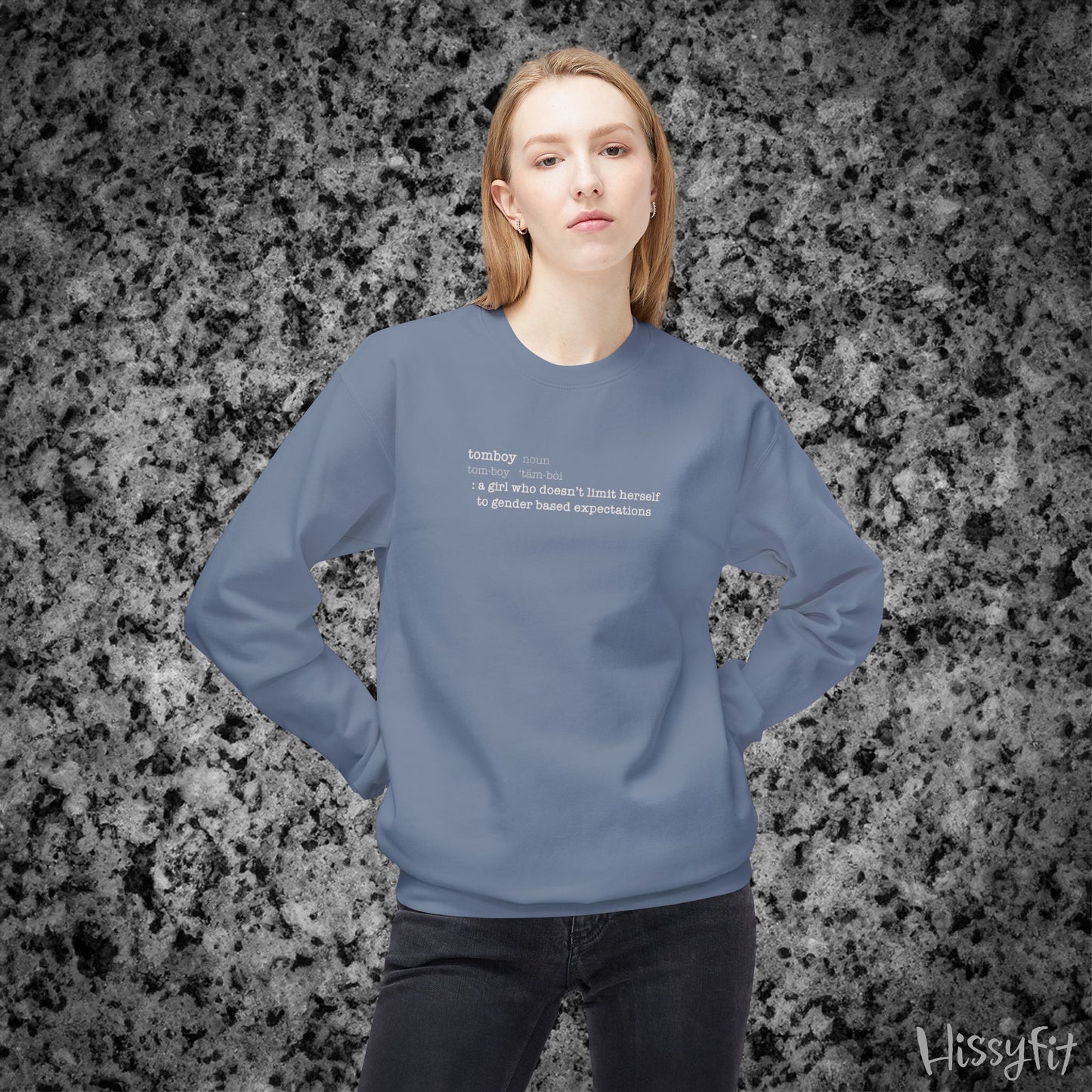 Person wearing a blue sweatshirt with text definition of "Tomboy" on a gray and black speckled background