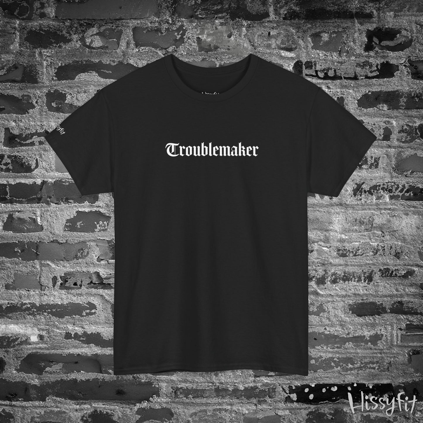 Black t-shirt with 'Troublemaker' text on a brick wall background