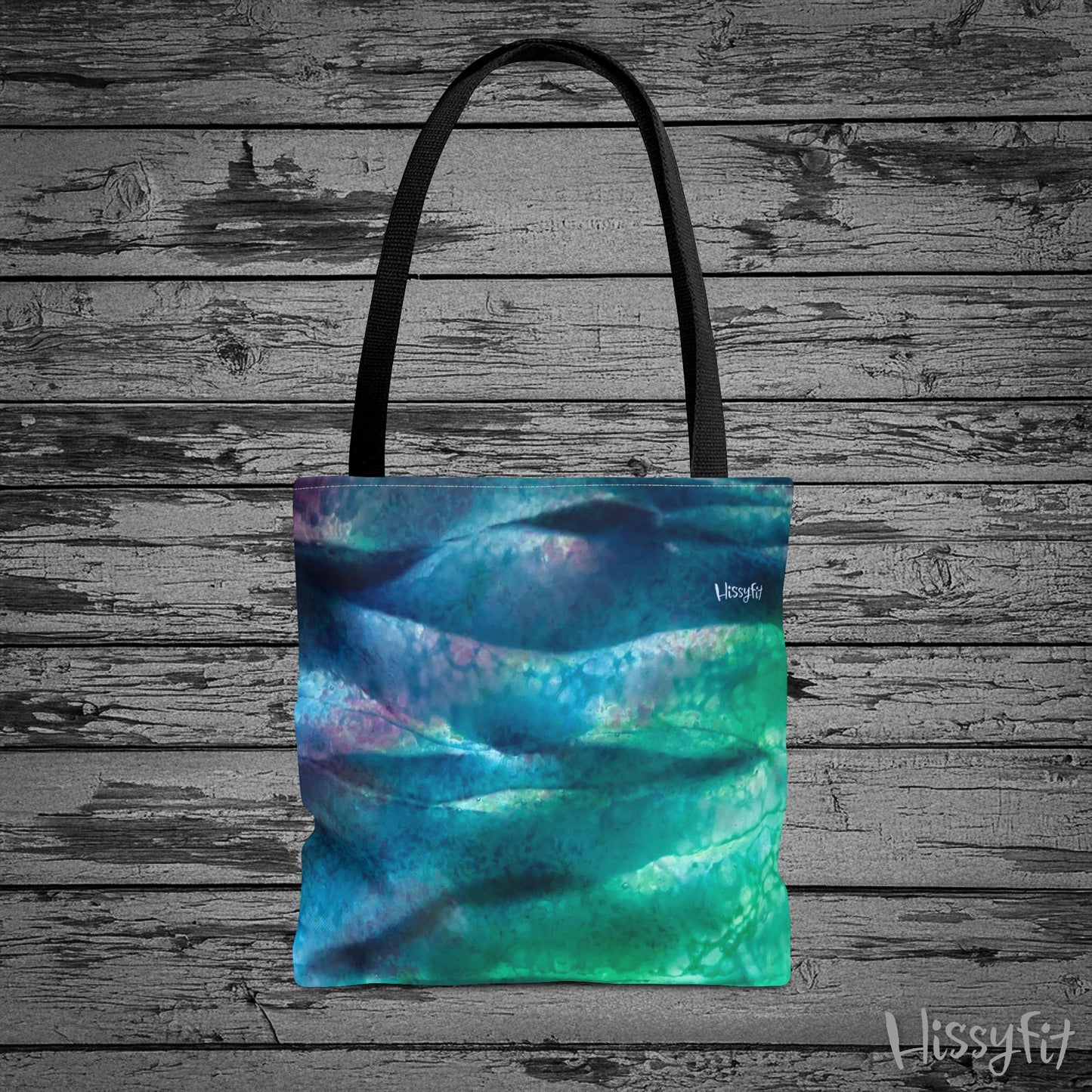 Tote bag with abstract blue and green design on a wooden surface