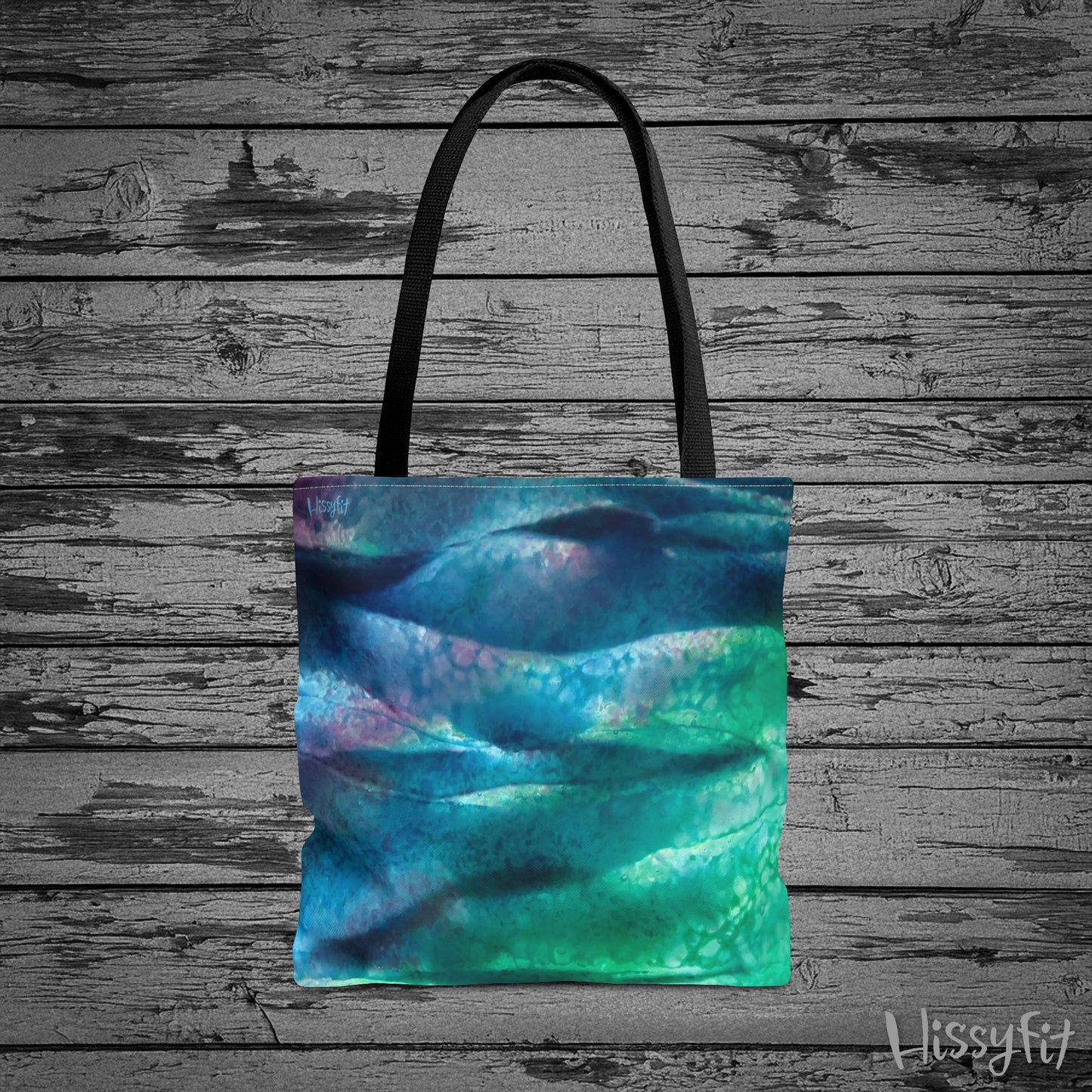 Tote bag with abstract blue and green design on a wooden surface