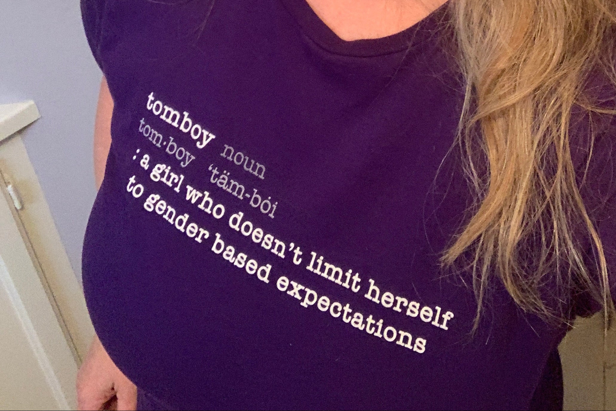 Woman wearing a purple shirt with text "Tomboy:Definition"